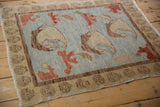 Oushak rug detail: powder blue field, cinnabar red blossom, and brown inner border.