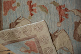 Folded corner of Modern Oushak rug, powder blue pile, cinnabar leaves, and woven geometric backing.