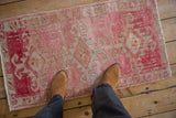 Distressed Kars rug's abrashed pink and beige ground beneath boots.
