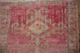Intact side cord selvage and raspberry pink pattern detail on distressed Kars rug.