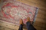 Vintage distressed Dargezine rug with abrash texture, cinnabar red, ivory floral pattern, and feet.