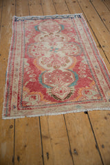 Distressed vintage Dargezine rug's fringed edge and worn red, ivory, and turquoise side border.
