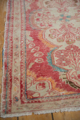 Distressed Dargezine rug corner showing worn cinnabar red pile, ivory, and fringe.