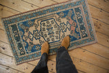 Vintage distressed Oushak rug showing worn pile with visible knot heads in blue, teal, beige.