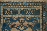 Distressed Oushak rug's geometric blossom detail in cobalt, teal, ivory.