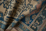 Folded distressed Oushak rug pile, geometric patterns in sandalwood, cobalt, and dusty teal.