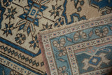 Distressed Oushak rug close-up: even wear, geometric border, field details in blues, beige, and pink.