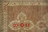 Distressed vintage Oushak rug's quatrefoil floral and meandering vine border in red, beige.