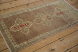 Distressed Oushak runner's machine-bound edge, showing pale coffee brown field and faded mauve blossoms.