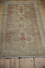 Distressed beige Oushak rug pile with pale mauve floral blossoms and visible wear.