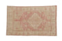 Distressed vintage Oushak rug with dusty pink diamond medallion, ivory field, and soft abrashes.