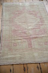 Soft abrashes on a dusty pink and beige vintage Oushak rug's geometric patterns.