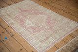 Distressed Oushak rug's faded dusty pink and ivory pile with soft abrashes and fringe.