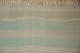 Textural view of distressed beige, ivory, and mint green horizontal bands on a Kilim runner.