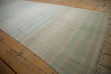 Distressed Turkish Kilim runner texture with horizontal beige, ivory, and mint bands, showing fringe.