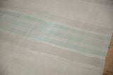 Distressed horizontal bands in muted beige and mint green on a vintage Kilim.