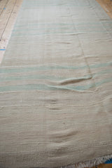 Distressed handwoven Kilim texture with horizontal bands in soft beige and mint green.