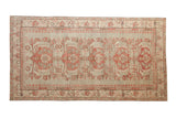 Distressed Kars rug with single column raspberry floral medallions on a muted sage green field.