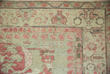 Vintage Kars rug corner detail: faded raspberry palmettes, soft green field, and visible wear.