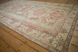 Distressed Kars rug showing faded raspberry red floral motifs on a subtle jade green field.