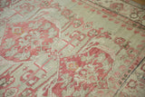 Distressed Kars carpet pile showing raspberry red floral palmettes, ivory details, and white knots.