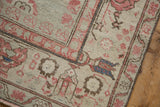 Vintage Kars carpet corner showing machine-bound side, distressed pile, pale raspberry and beige floral motifs.