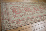 Distressed Kars rug detail: faded raspberry palmettes on a pale jade green field.