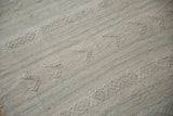 Distressed vintage Turkish Kilim rug featuring raised geometric texture in beige and blue.