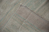 Textured distressed surface with raised woven elements and fringed edge of a vintage Turkish Kilim.