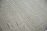Raised woven geometric patterns and vine-like embossing on a distressed beige Kilim.