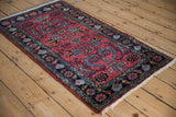 Raspberry red field with blue floral tendrils, bordered by navy Herati motifs.