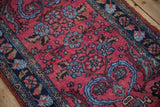 Mehreban rug's raspberry red field with sky blue blossoms, dark tendrils, and a navy Herati border.