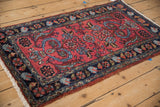 Vintage Mehreban rug's raspberry red field with expressive serrated leaves, blue tendrils, and floral motifs.