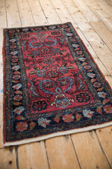 Vintage Mehreban rug corner with navy floral border and raspberry field of tendrils.