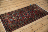 Intricate floral pinwheel blossoms on a red field and border of a vintage Sarouk runner with ivory fringe.