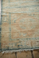 Antique distressed Peking runner corner: soft beige pile, blue border, and light fringe.