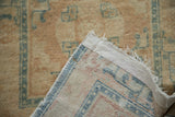 Folded corner of antique Peking runner, showing original selvage, distressed beige pile, woven foundation.