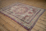 Persian Kerman antique rug corner, intricate floral field, navy and ivory scrolling borders.