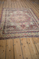 Antique Kerman rug detail: ivory, cochineal red thousand flower field, scrolling vines, worn edge.