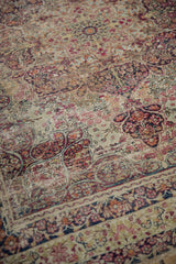 Intricate faded floral pattern and visible wear to foundation on antique Kerman rug.