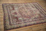 Intricate floral field and borders of antique Kerman rug in ivory, raspberry, and navy.