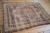 Worn floral borders with scrolling vines and tattered edge of this antique Kerman rug.