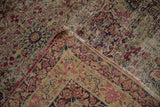 Folded corner of a Persian Kerman rug, showing floral motifs, abrash, and foundation wear.