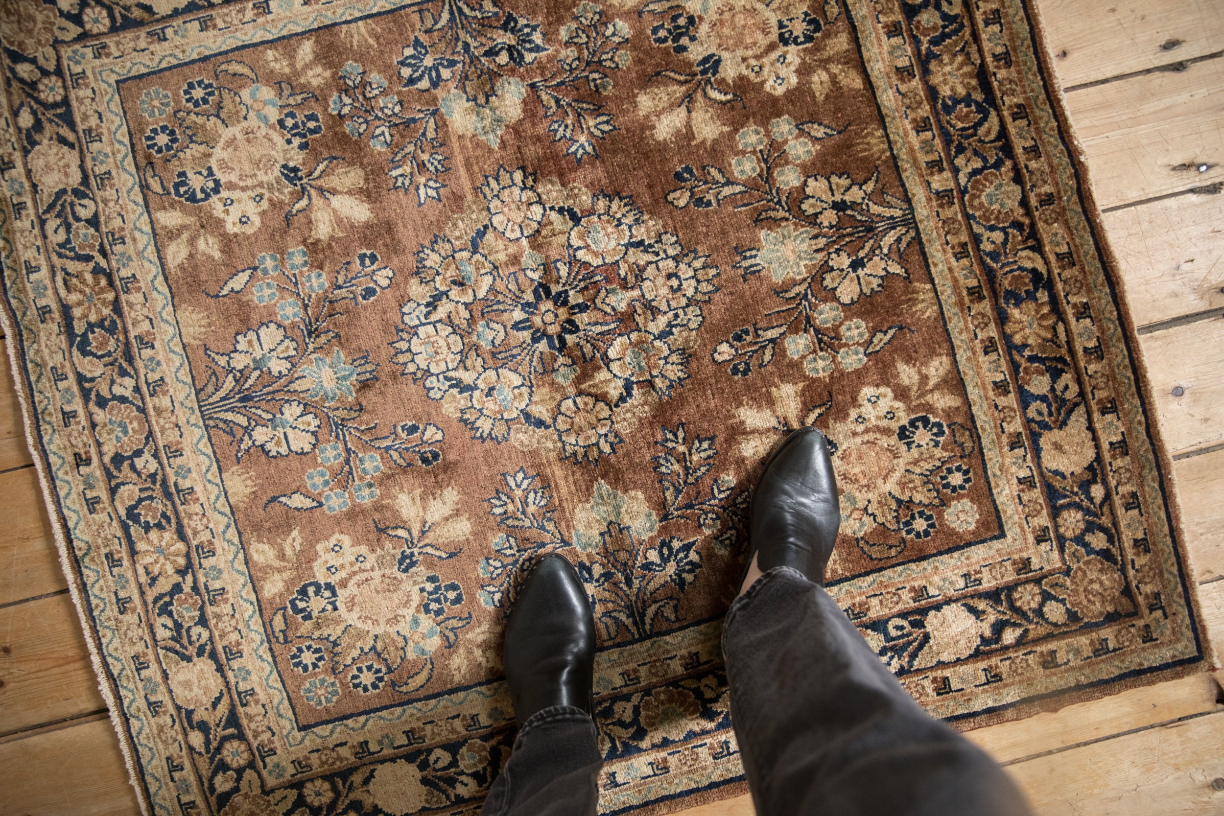 Traditional Persian Sarouk rug with chestnut field, blue and ivory floral motifs, feet for scale.