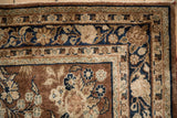 Vintage Sarouk rug corner with meandering vine border and chestnut, navy floral field.