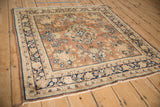 Vintage Sarouk rug corner: dark navy palmette border on a chestnut floral field.