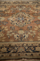Detail of hand-knotted Sarouk rug showing chestnut brown field, ivory, navy floral vines.