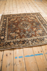 Vintage Sarouk rug lower edge with ivory fringe, brown field, and navy floral palmette border.