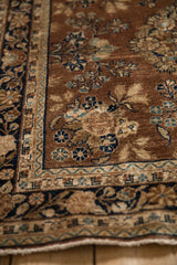 Vintage Sarouk rug's corner with chestnut field, navy blue floral, and meandering vine border.