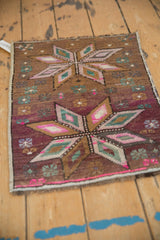 Distressed Kars rug, close-up of geometric starburst with worn pile in mauve, magenta, teal.